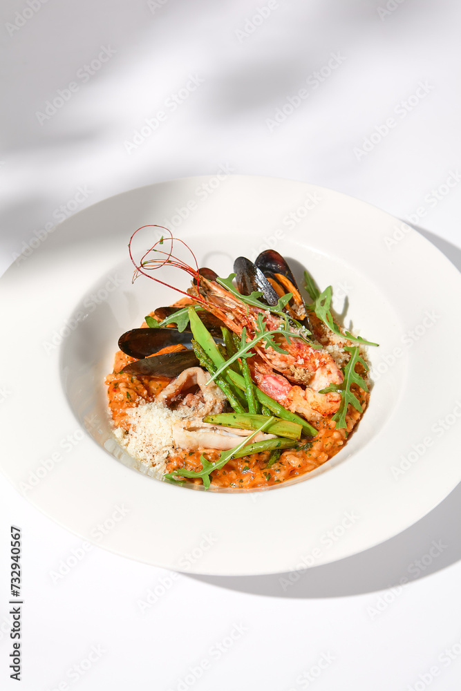 Tomato seafood risotto casting soft shadows on white, an ideal representation of Italian cuisine and summer dishes Tomato seafood risotto casting soft shadows on white, an ideal representation of Italian cuisine and summer dishes