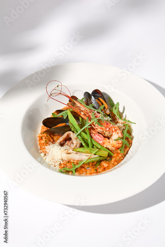 Tomato seafood risotto casting soft shadows on white, an ideal representation of Italian cuisine and summer dishes