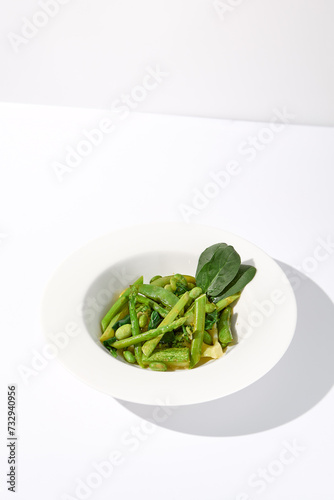 Fresh green vegetable garnish featuring asparagus  zucchini  and edamame beans on isolated white background