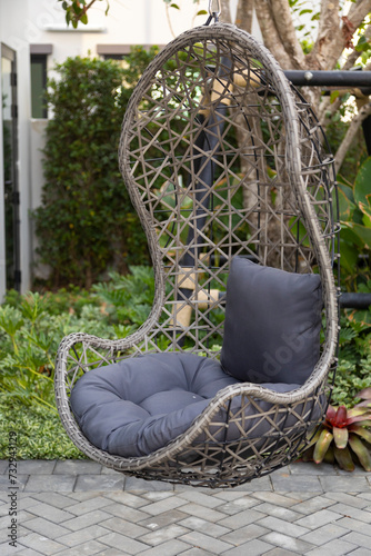 Rattan wicker cocoon garden swing chair hanged on frame. Recreation scene with a hammock-chair in the backyard of the house. Relax concept with hammock chair .