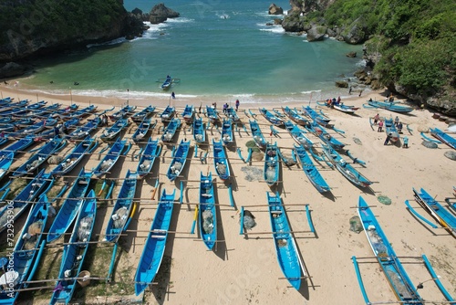 aerial view of white sandy beach in tropical island. people enjoying vacation in tropics. blue fishing boat by the beach.