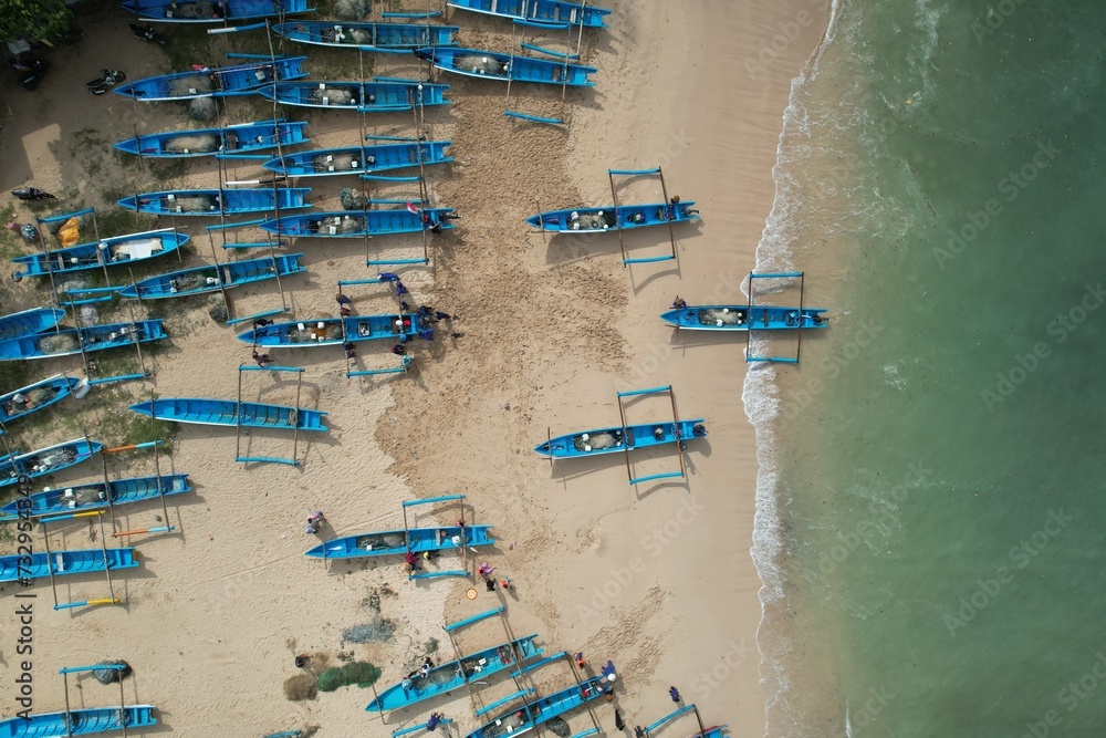 aerial view of white sandy beach in tropical island. people enjoying vacation in tropics. blue fishing boat by the beach.