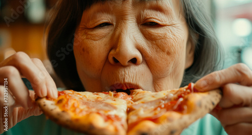 Senior Asian woman eating a slice of pizza photo