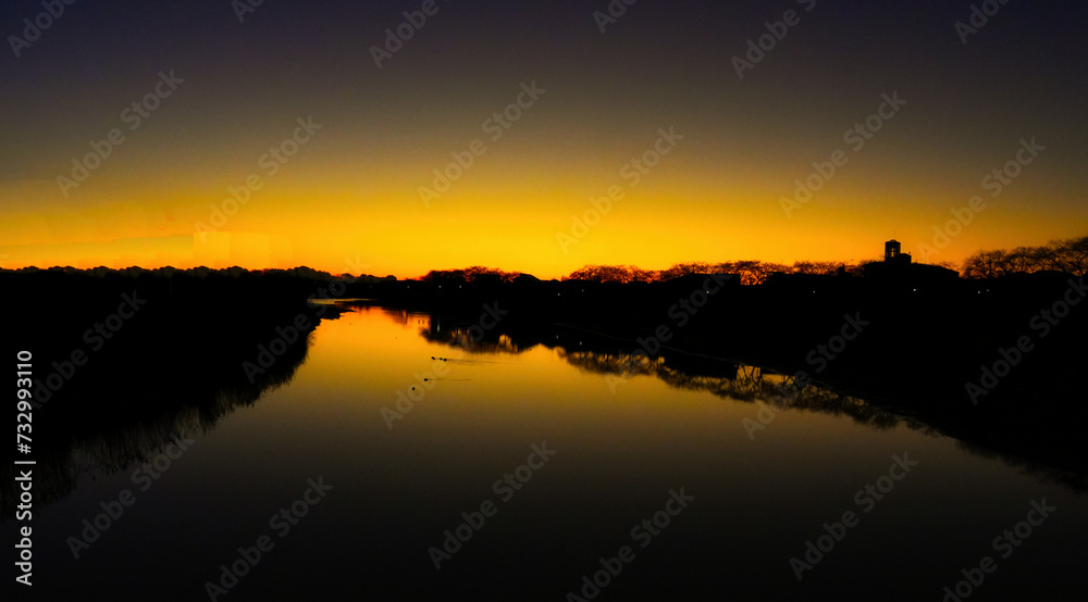 川の朝焼けの風景です。キラキラ黄金色の川の水面の絶景風景です。