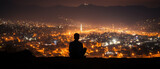 a sitting on a hill overlooking a city at night