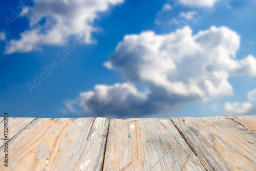 photo of a wooden board with a blue sky and clouds in the background