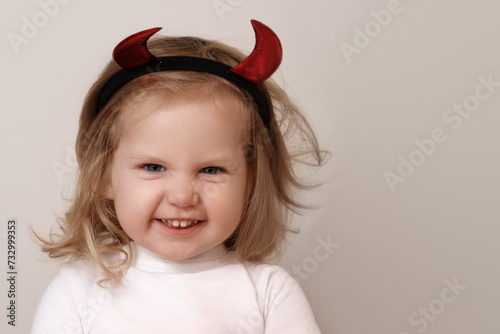 Beauty baby girl. Halloween background with happy kid and space, funny child, cute little girl with costume horns having fun and makes face. Food, thanksgiving, hallowen and party theme