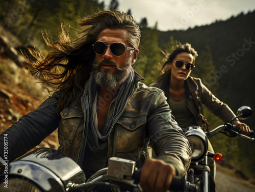 stylish hipster middle age couple - bearded brutal male in sunglasses and leather jacket sitting on 2 two retro motorcycles and sensual girl riding together, ride on forest road background