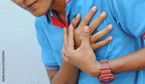 hand hold chest with heart attack symptoms, asian man have chest pain caused by heart disease, leak, dilatation, enlarged coronary heart, press on the chest with a painful expression photo