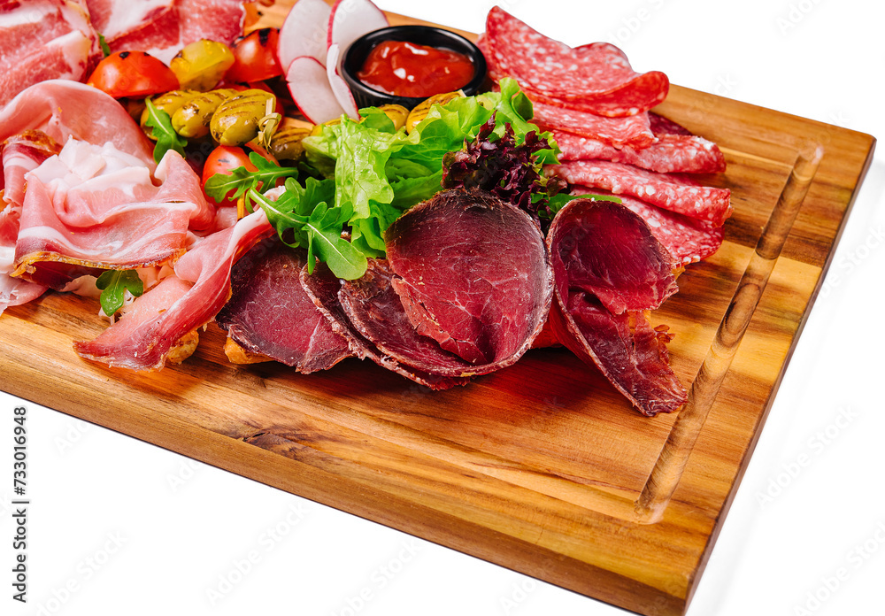 Variety of meats, sausages, salami, ham, olives, laid out on a wooden board