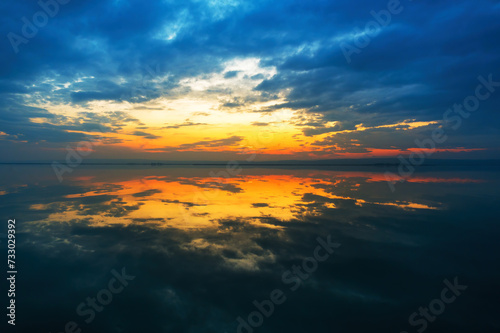 Dramatic sunset at the Lake Neusiedlersee in Austria with colorful orange and red illuminated cloudy sky