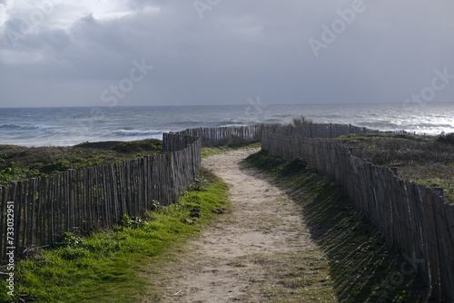 A small path through some wooden fence to reach the shore on a stormy day. Batz-sur-Mer  France - February 10  2024.