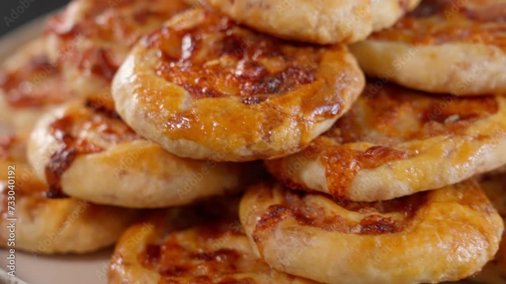 Close-up of freshly baked homemade ham and cheese buns. Mini pizza rotating in a circle, front view, macro Close-up of freshly baked homemade ham and cheese buns. Mini pizza rotating in a circle, front view, macro