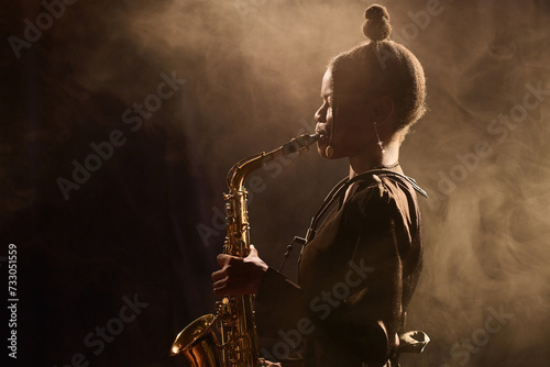Canvas Print Ambient side view portrait of Black young woman performing jazz music on stage i