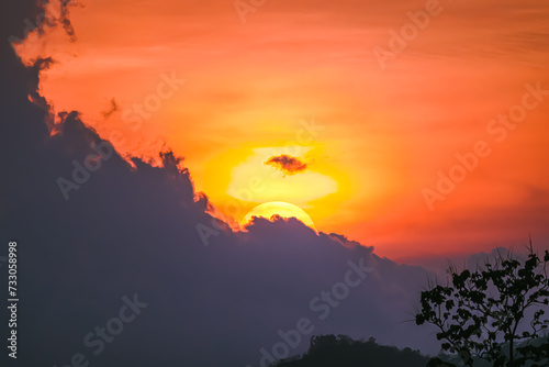 Top view of the sunset is getting disappearing in the sky. Clouds are orange yellow and pink with colorfull. There are many layers of mountains below. The idea for natural wallpaper with copy space. © Pang wrp