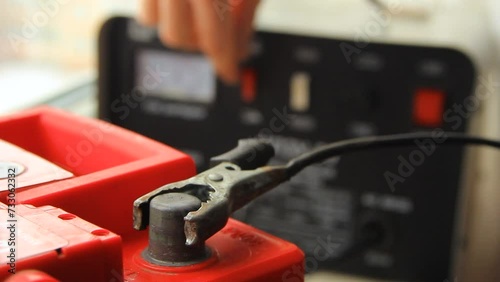 A man's hand attaches a car terminal to a battery