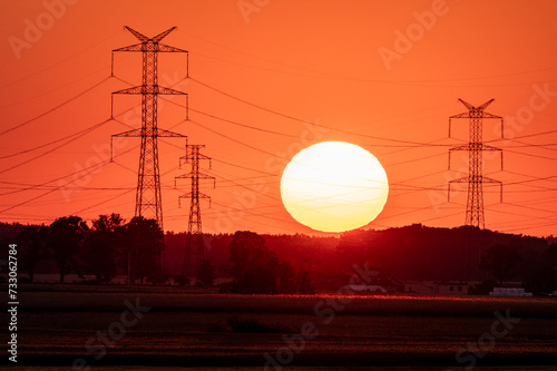 linia energetyczna i słońce zachodzące na czerwonym tle photo