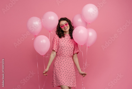 pretty young woman posing isolated on pink studio background with pink air balloons