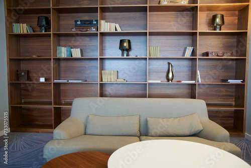 BRESLAU, POLAND - 15 JUN 2018: Light-coloured sofa in front of a shelf with various decorative items in an executive lounge of a luxury hotel