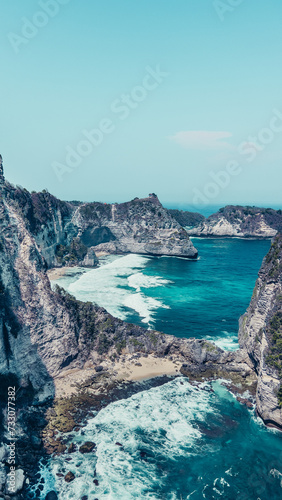Aerial perspective of a rocky coastline and vivid turquoise waters as seen from an airplane