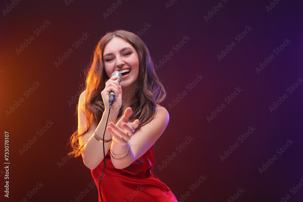 Emotional woman with microphone singing in color lights. Space for text Emotional woman with microphone singing in color lights. Space for text