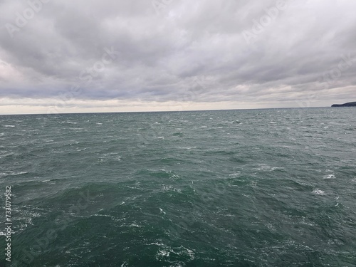 Ocean from a boat on the way to shore, with grey clouds above