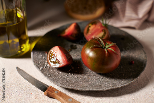 Red-green tomatoes close up on a stone plate with olive oil