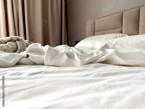 Fototapeta Naklejka Na Ścianę i Meble -  Empty bed after a night of sleeping. Striped white satin bed linen. Mess on bed. Scandinavian interior