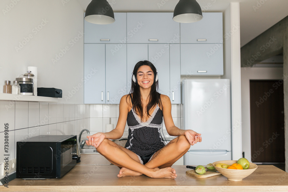 attractive smiling woman in pajamas having breakfast in kitchen attractive smiling woman in pajamas having breakfast in kitchen