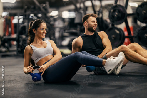 Fitness couple is doing kettlebell twist in a gym togehter.