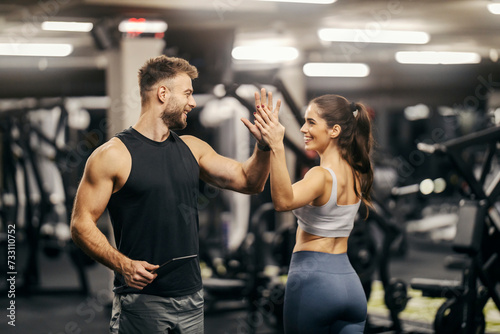 A sportswoman giving high five to her fitness instructor in a gym.