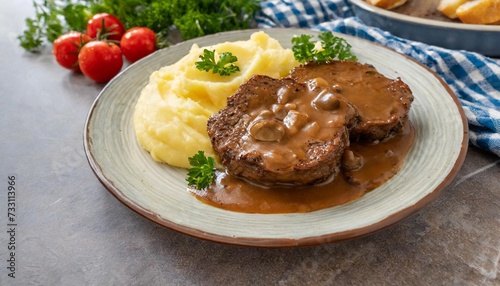 delicious home cooked salisbury steak with thick luscious brown mushroom gravy served with mashed potatoes on a plate traditional american cuisine dish specialty for family dinner holiday celebration