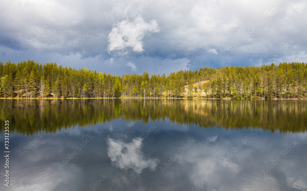 Dramatic cloudscape with a raising storm on a finnish lake surrounded by forest. Deep nature in Lapland, Finland.