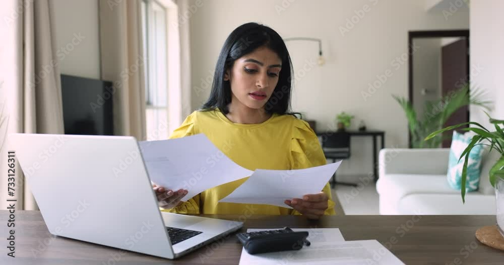 Desperate young Indian woman makes expenses and personal earnings analysis feels disappointed looks desperate, experiences lack of money to pay taxes and bills. Overspending, debt, financial troubles