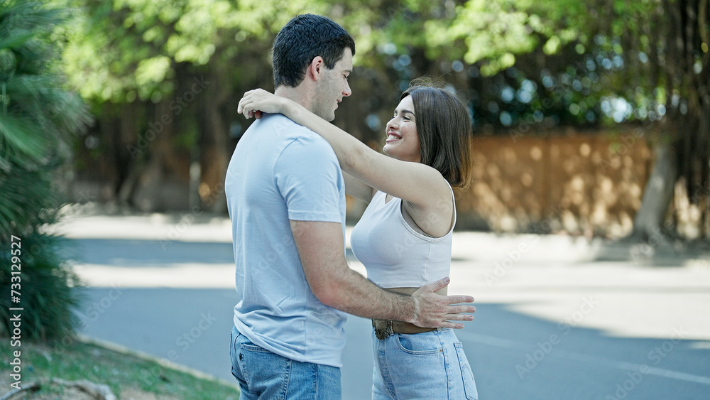 Beautiful couple hugging and looking each other smiling at park Beautiful couple hugging and looking each other smiling at park