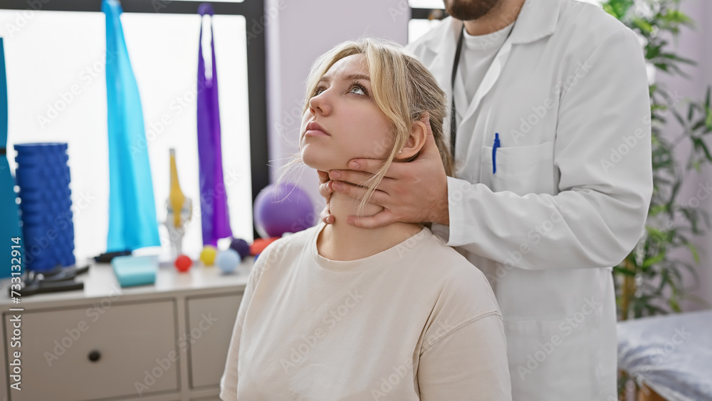 In a rehab clinic, a male physiotherapist administers neck therapy to a female patient indoors.