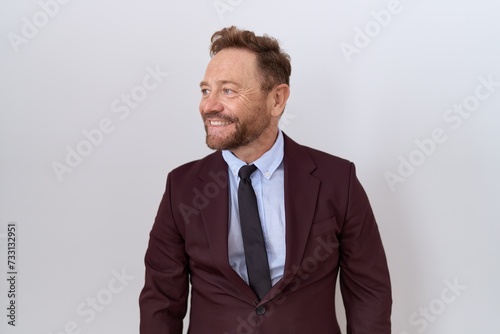 Middle age business man with beard wearing suit and tie looking away to side with smile on face, natural expression. laughing confident.