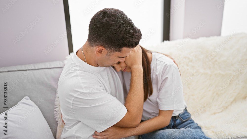 A couple in love embraces tenderly on a couch, symbolizing relationship and intimacy in a cozy home setting.