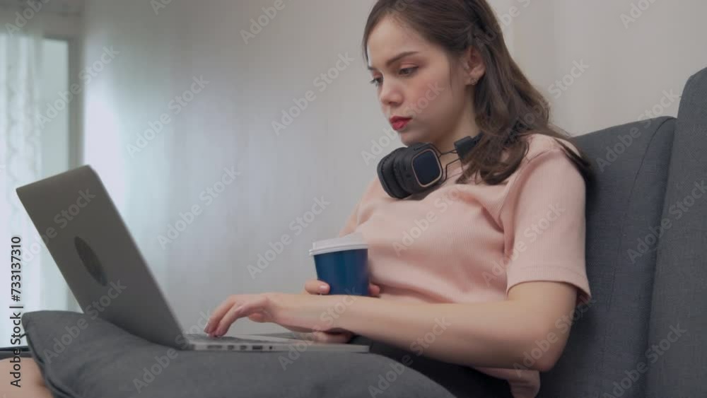 Asian woman wearing casual clothes uses computer while studying online at condo