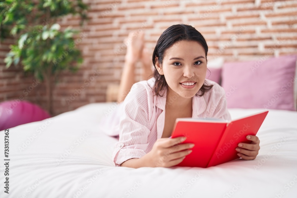 Young hispanic woman reading book lying on bed at bedroom Young hispanic woman reading book lying on bed at bedroom