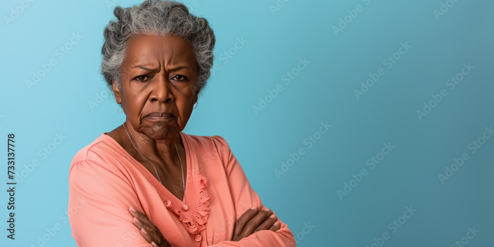 Grumpy senior black woman looking at camera with resentment and disapproval, on solid background with copy space.