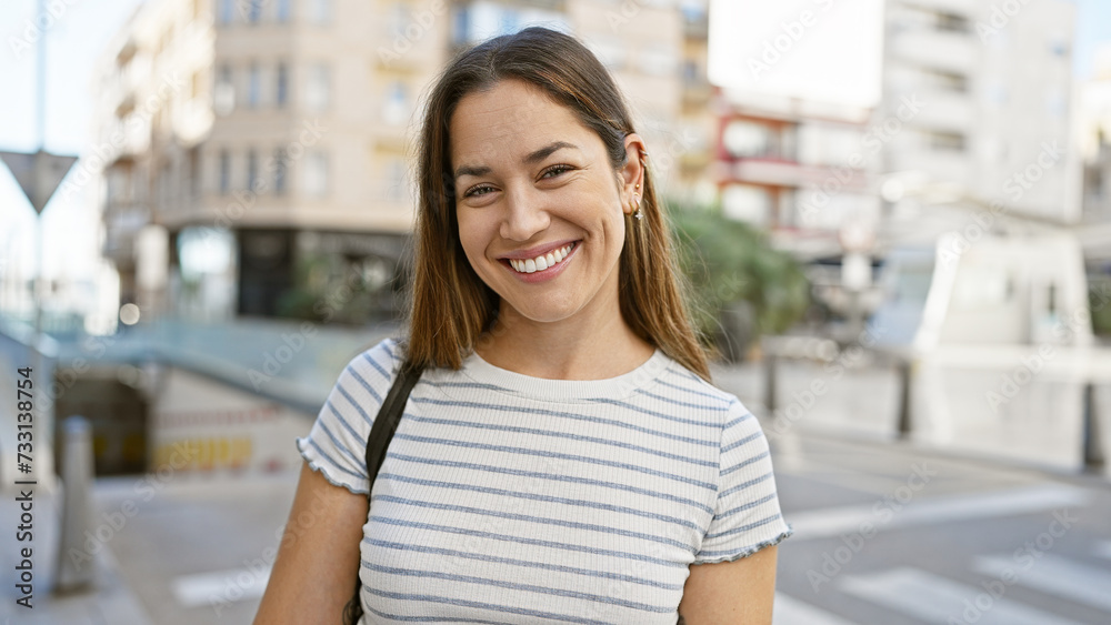 Smiling young woman with long hair posing in a lively urban street setting