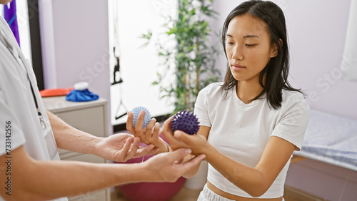 A woman patient examines rehabilitation equipment with a therapist in a clinic's treatment room.
