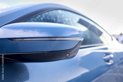 Luxury car detail left back mirror parking camera closeup. Road safety concept. 360 terrain surround system option of modern car. Side view rearview mirror of modern car with around view camera.