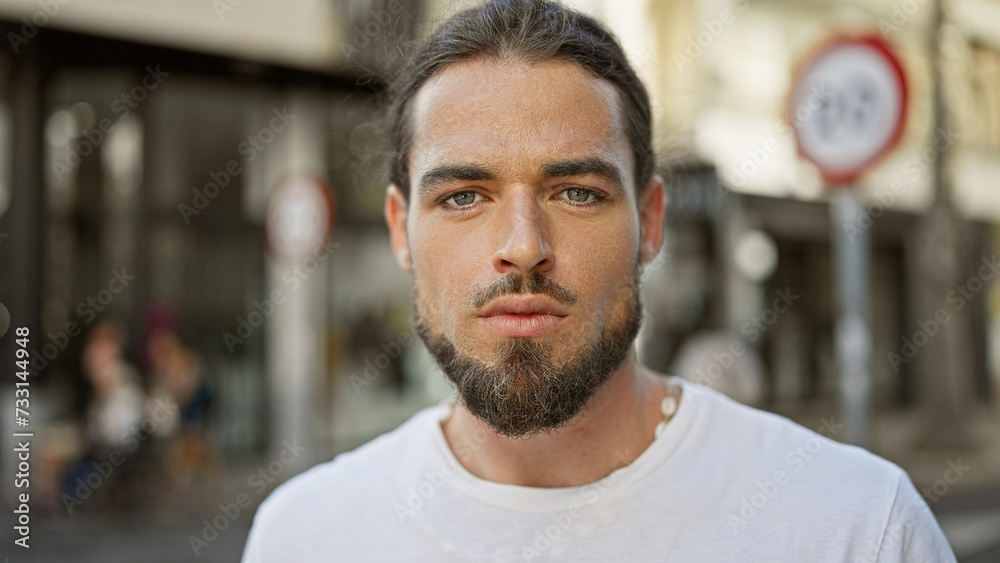 Young hispanic man standing  with serious expression at street