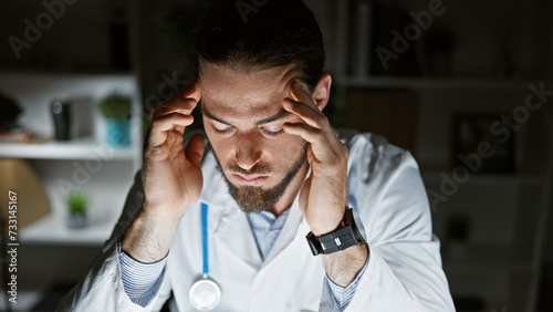 Young hispanic man doctor suffering for headache at the clinic