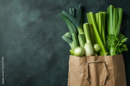Paper grocery bag filled with various fresh green vegetables against a dark background