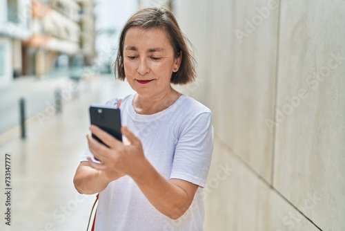 Middle age woman using smartphone with serious expression at street