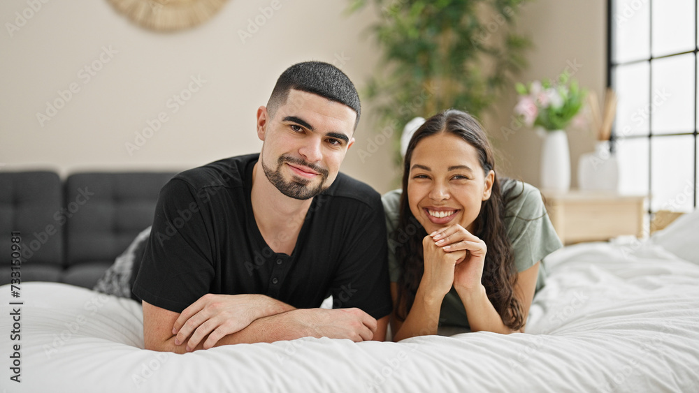 Smiling, beautiful couple lying on comfortable bed, relishing their happy relationship and love in the cozy interior of their bedroom. Smiling, beautiful couple lying on comfortable bed, relishing their happy relationship and love in the cozy interior of their bedroom.