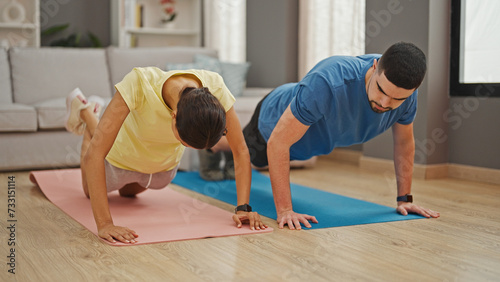 Beautiful couple showcasing power and love, training together with indoor push up workout at home